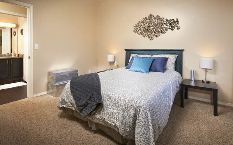 Spacious master bedroom with attached bathroom at Crossroads at City Center Apartments in Aurora, Colorado