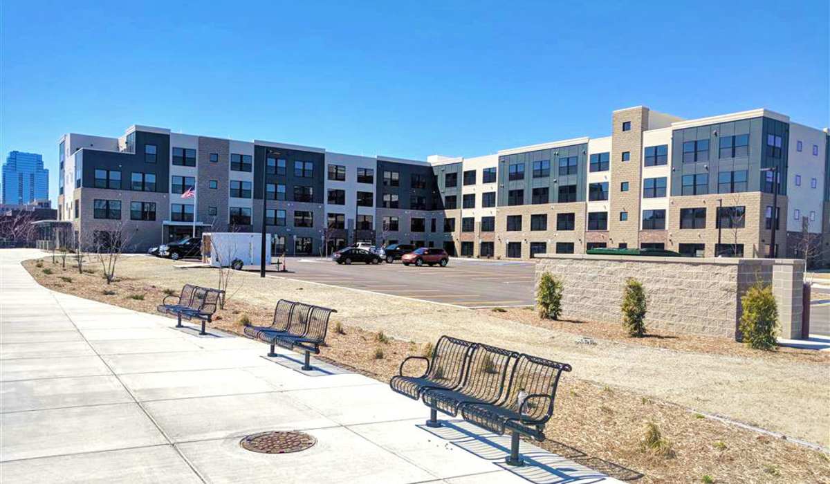 Modern apartment community with landscaped grounds and benches along the walkway at Grand View Place in Grand Rapids, Michigan