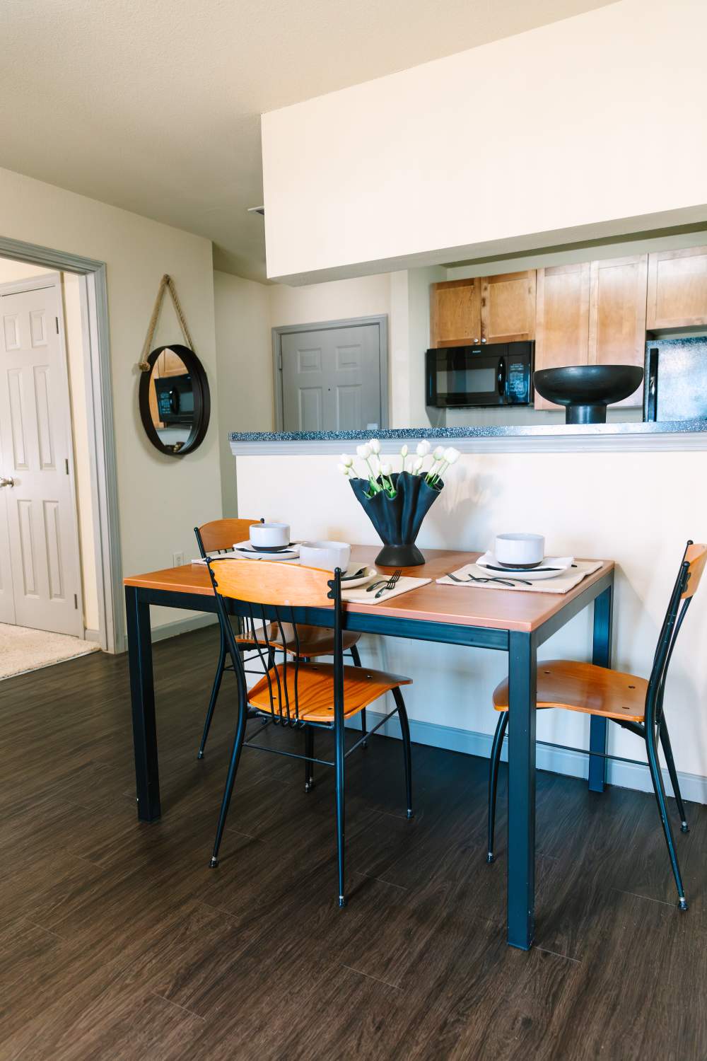 Cozy dining area with wood table, place settings, and kitchen pass-through counter at The Holly in Lubbock, Texas