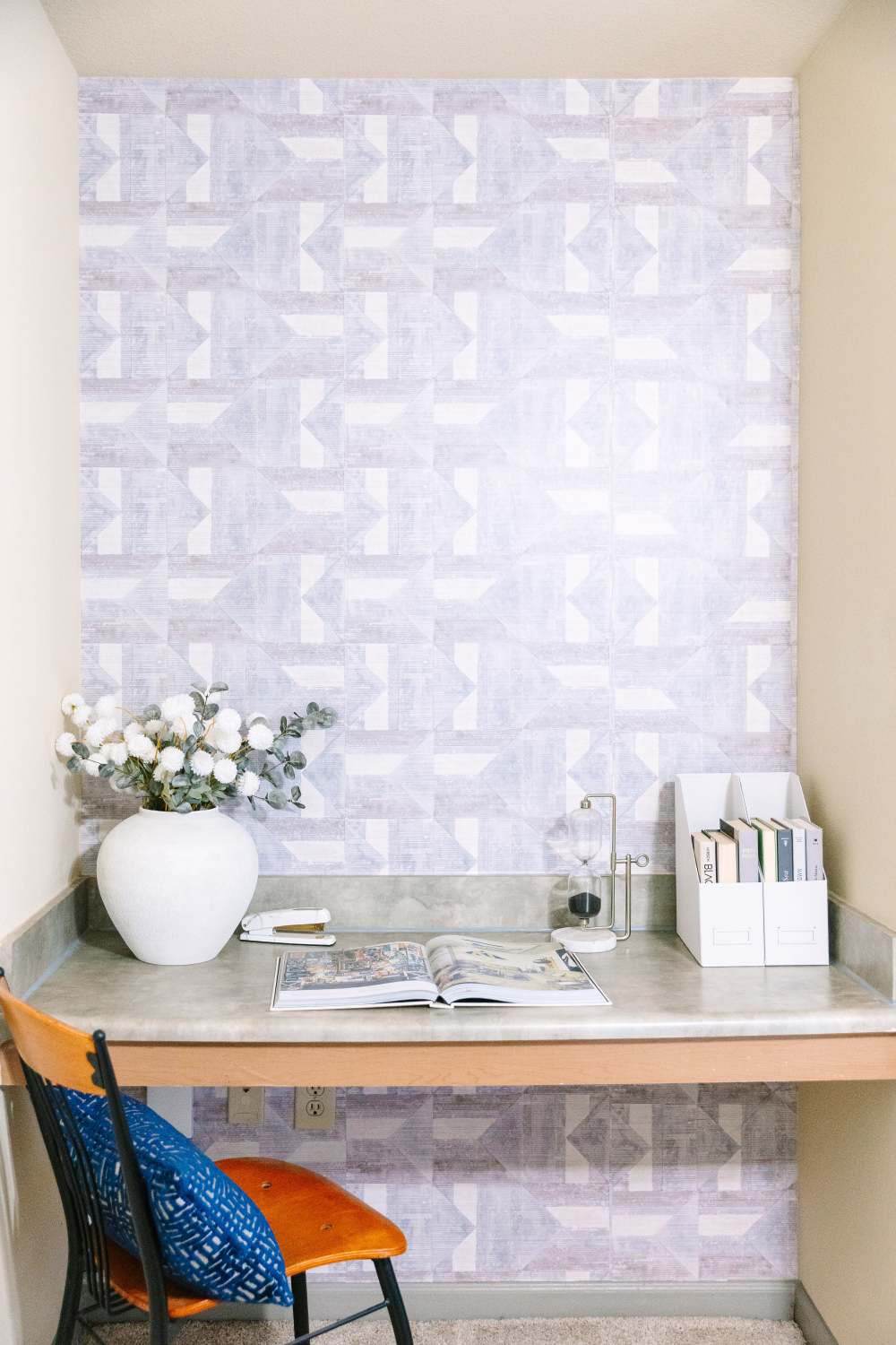 Work nook with desk, chair, vase with flowers, books, and decorative accents at The Holly in Lubbock, Texas