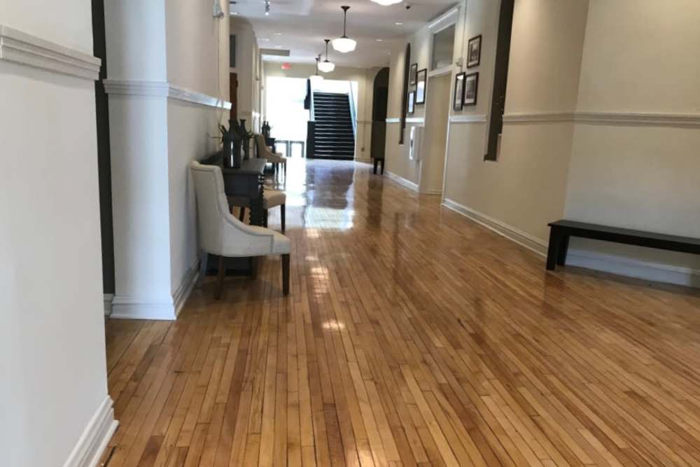 Wood-style flooring in a bright hallway with seating and decorative plants at Cavalier Greene in Corunna, Michigan