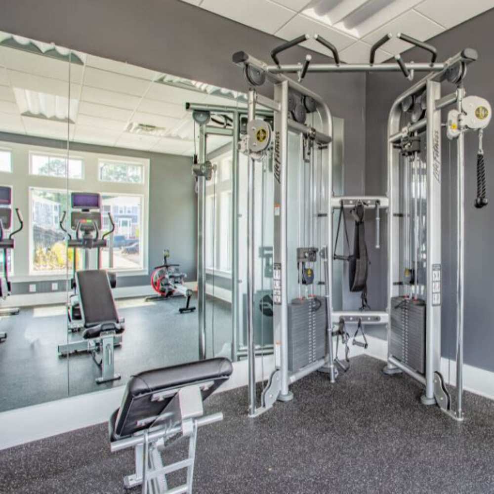 Modern gym with workout equipment and mirrors at The Apartments At Kelton Station in Williamsburg, Virginia
