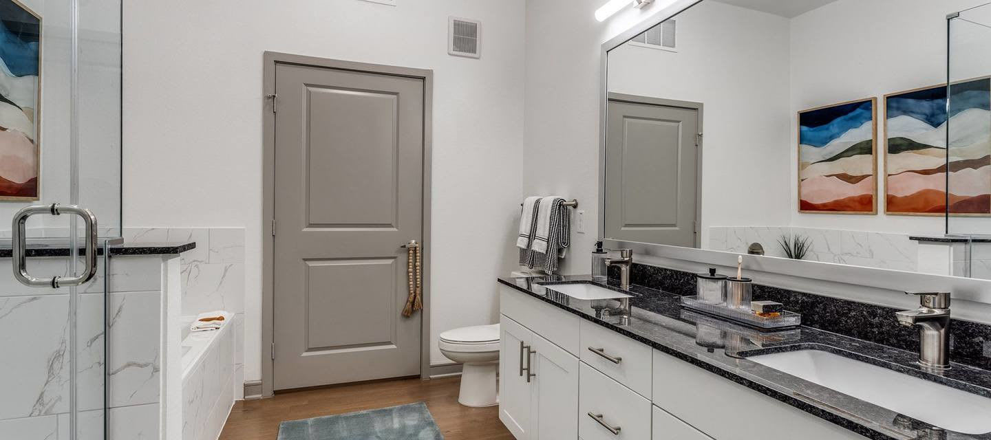 Bathroom with glass shower and marble countertops at Luxia Gallery House, Farmers Branch, Texas