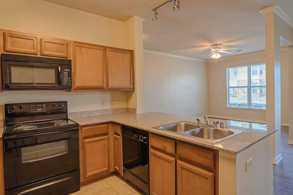 Wooden cabinets and black appliances in kitchen at Blue Ridge in Midland, Texas