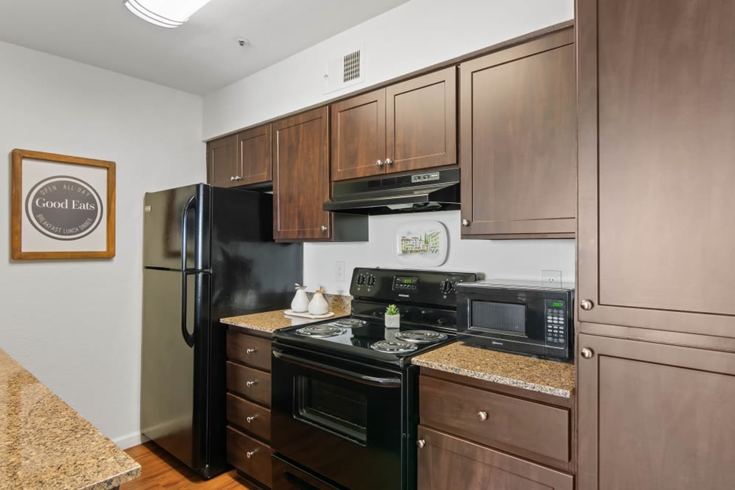 Kitchen with dark cabinets and black appliances at Cabrillo Apartments in Scottsdale, Arizona