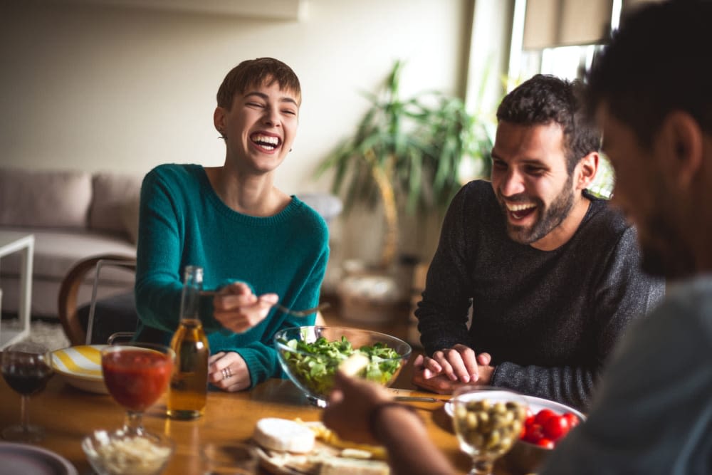 Residents enjoying a home-cooked meal and lively conversation in their new apartment at Thirteen15 in New Orleans, Louisiana