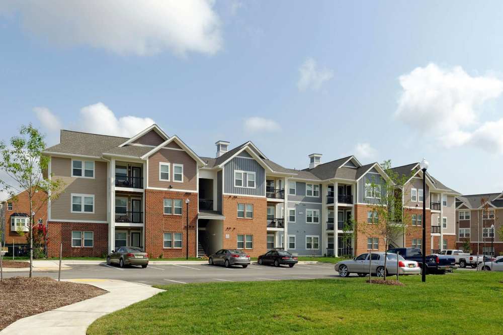 Modern apartment complex with spacious parking and green landscaping at Adams Crossing in Waldorf, Maryland