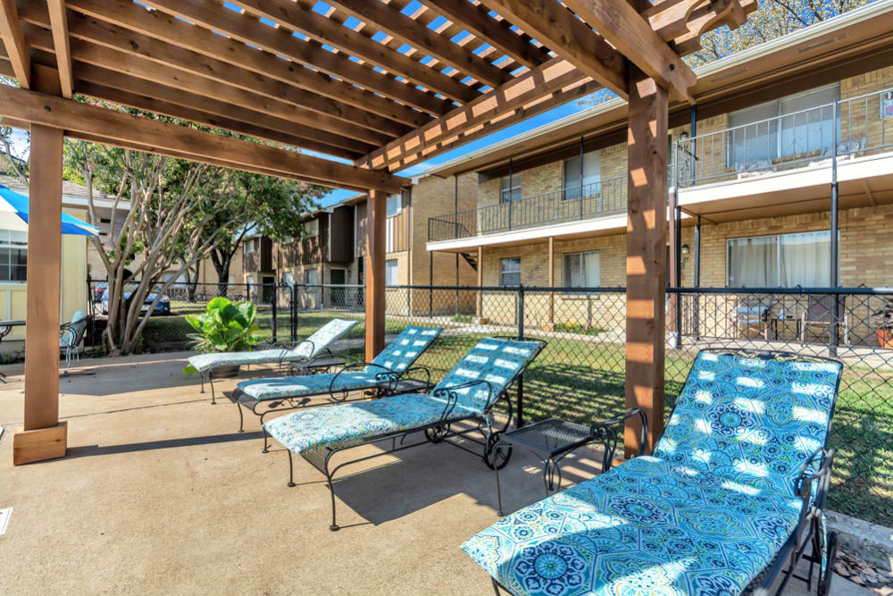 Outdoor lounge chairs by the pool at Franciscan Apartments in Garland, Texas