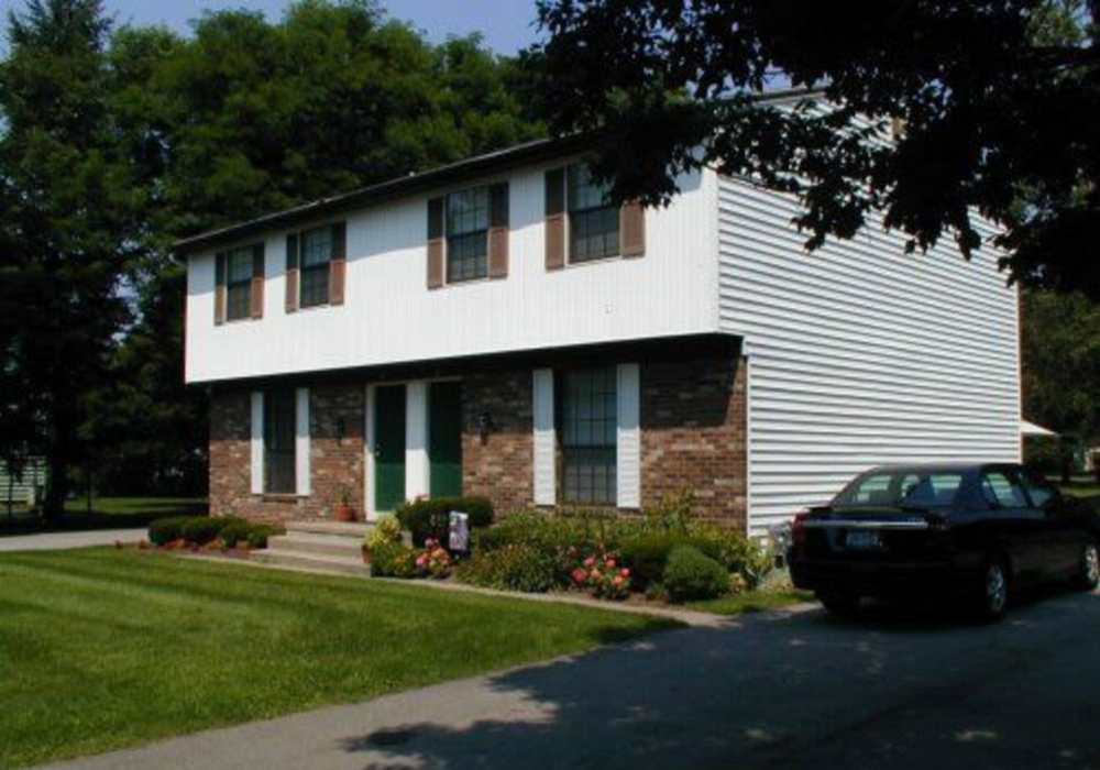Two-story apartment with green door and garden at Jefferson Manor Townhomes in Fairport, New York