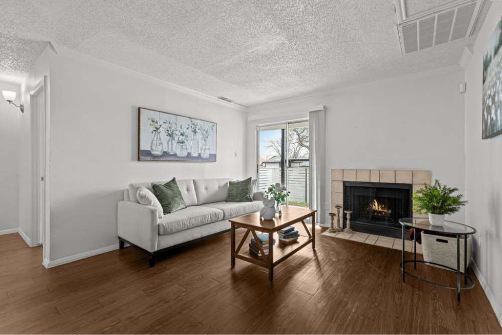 Bright living room with wood-style flooring, cozy fireplace, and modern furniture accents at The Fielder in Austin, Texas