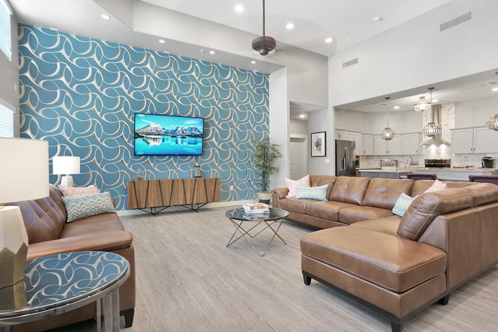 Large living area with a TV mounted on the wall surrounded by brown couches at Hacienda Del Rey in Litchfield Park, Arizona