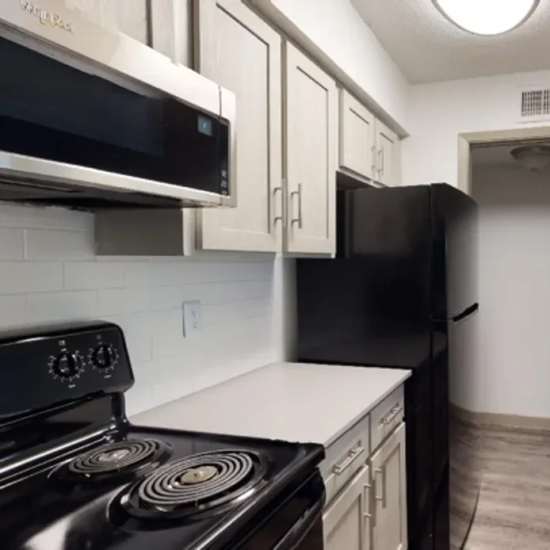 Modern kitchen with black appliances and granite countertops at The Larsen Apartments in Dallas, Texas