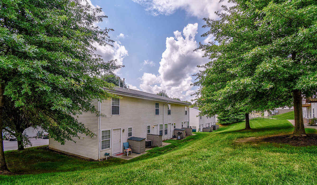Back view of apartment and grassy hill with large trees at Greene Glen in Morgantown, West Virginia