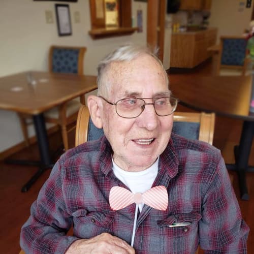 A resident holding a bowtie up to their neck at Alderbrook Village in Arkansas City, Kansas
