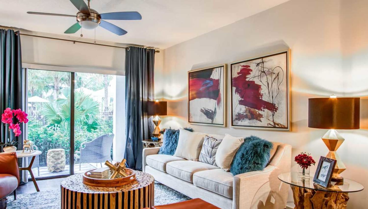 Model living room with a ceiling fan opening onto a private balcony at Eterno in Pompano Beach, Florida