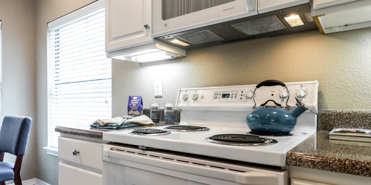 Bright kitchen with laminate counters, white cabinets, and white appliances at Marquis at Waterview in Richardson, Texas