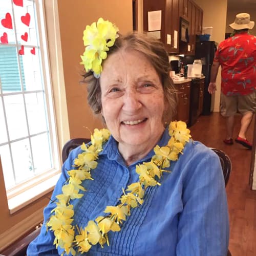 Resident at a party wearing a flower necklace at Oxford Glen Memory Care at Owasso in Owasso, Oklahoma