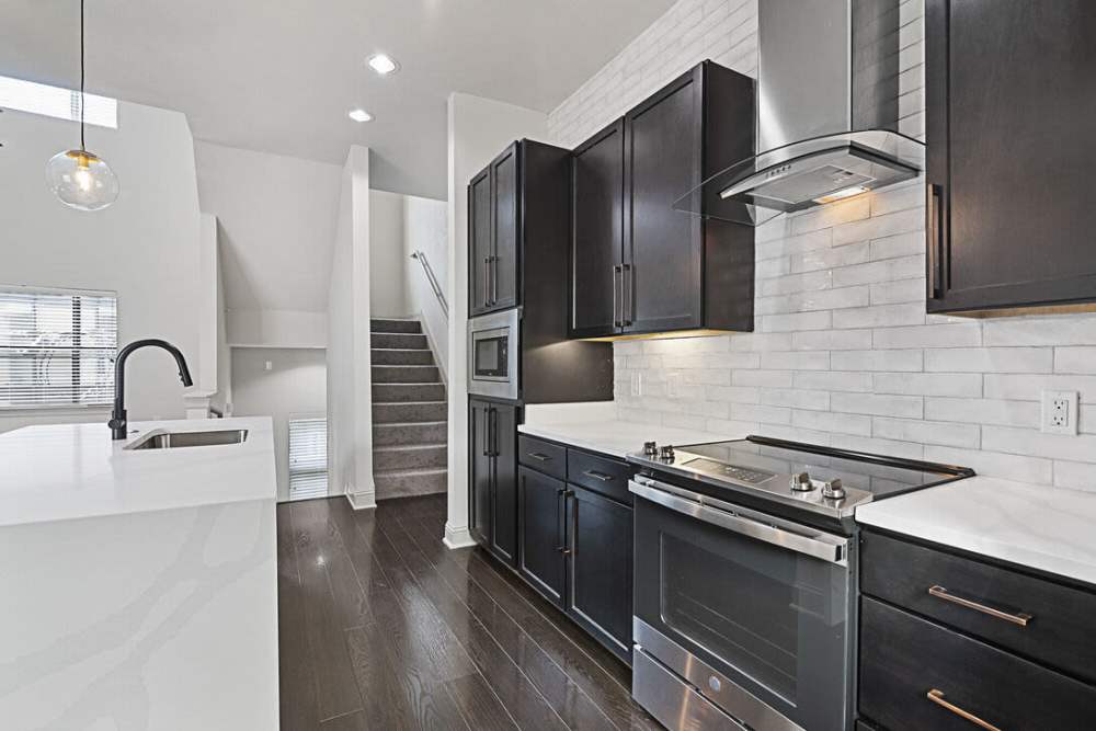 Kitchen withh black cabinetry and wooden flooring at Domain Memorial in Houston, Texas