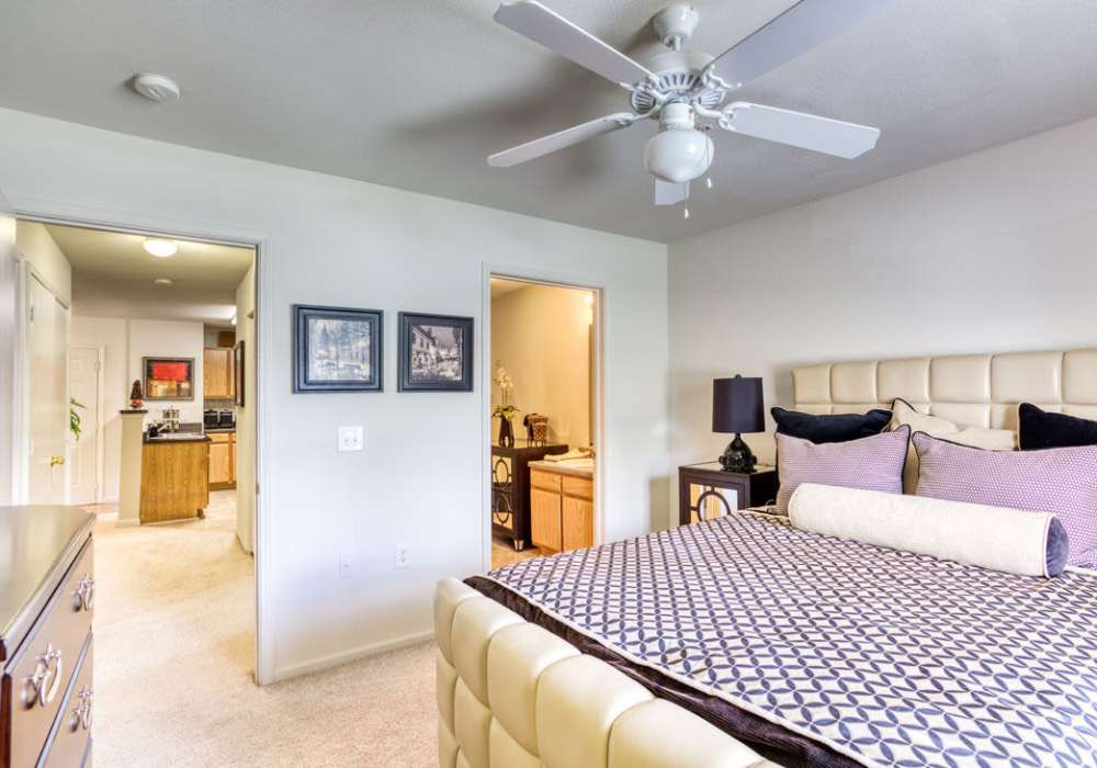 Bedroom with connecting bathroom, plush carpeting, large closets and a ceiling fan at Eagle Point Village in Fayetteville, North Carolina