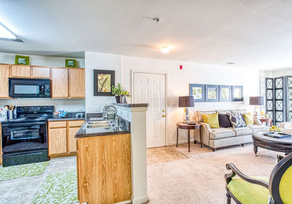 Open kitchen with bar counter connecting to living room, waterfall sink, stove, microwave and granite countertops at Deer Meadow Village in Columbia, South Carolina 