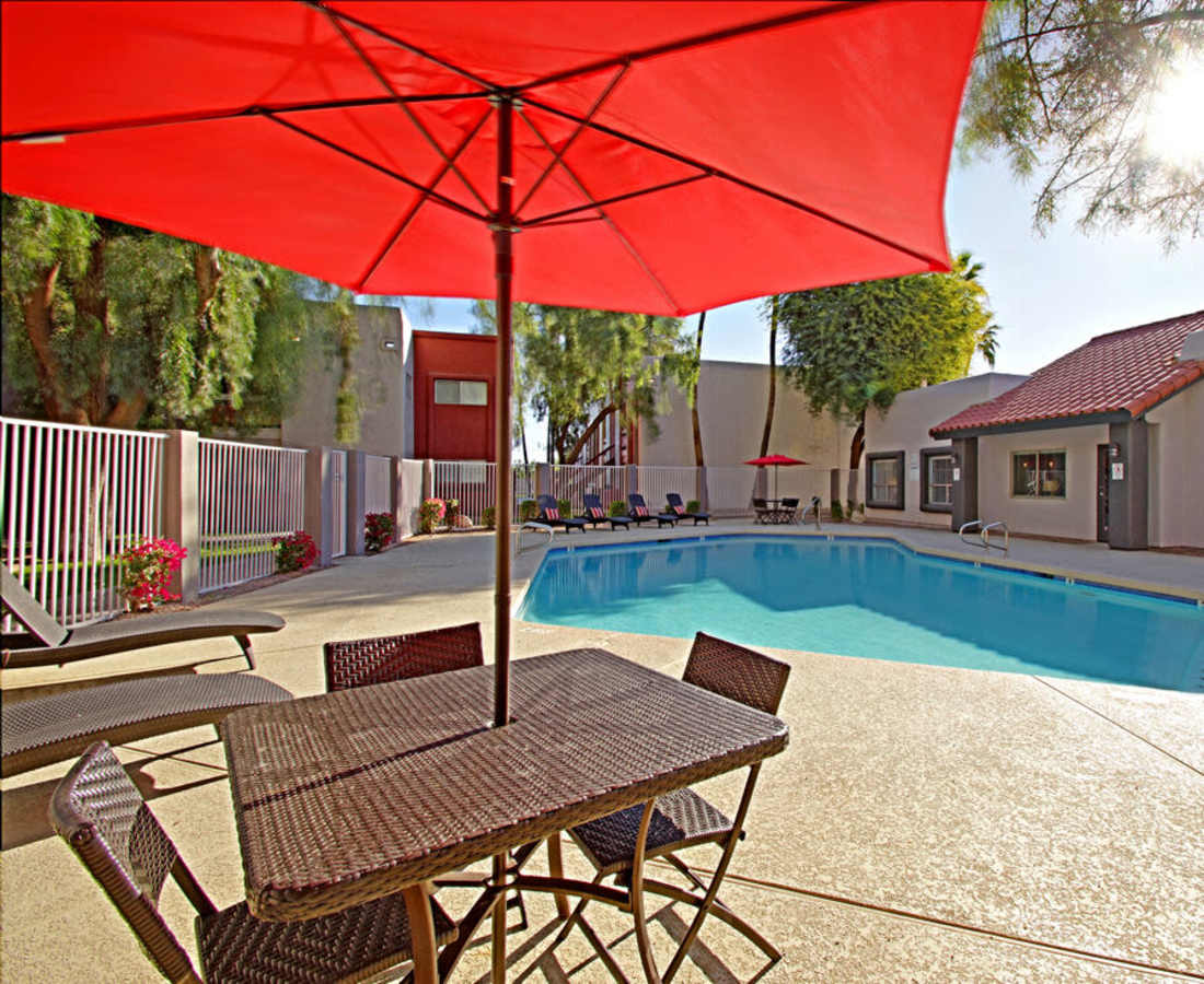 Sitting area with a large umbrella by the pool at 544 Southern Apartments in Mesa, Arizona