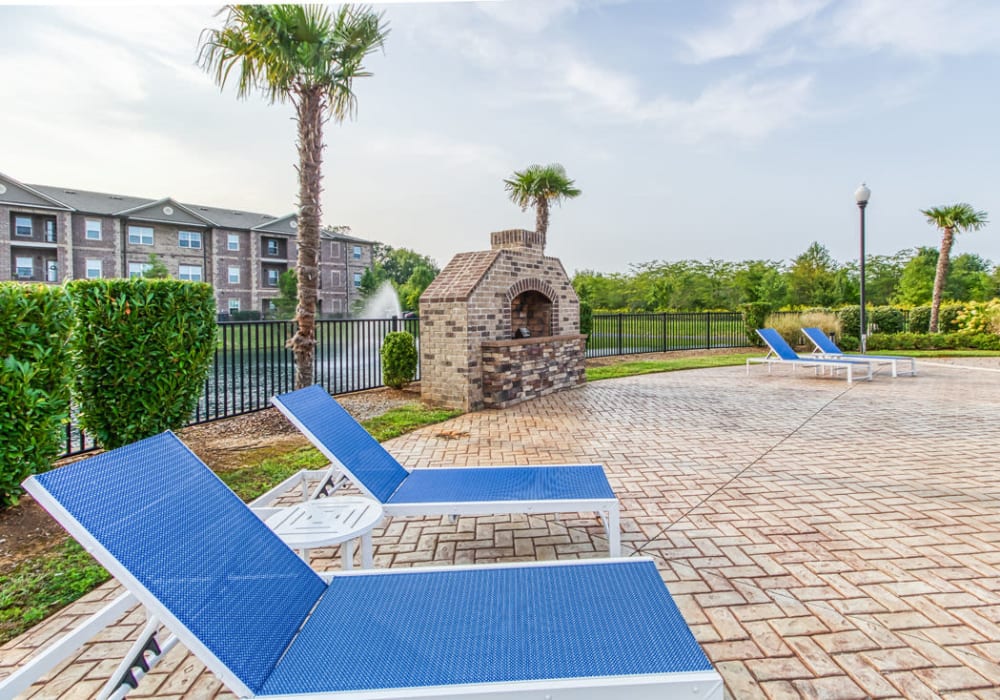 Lounge chairs and fireplace surrounded by palm trees in the pool area at Everwood at The Avenue in Murfreesboro, Tennessee