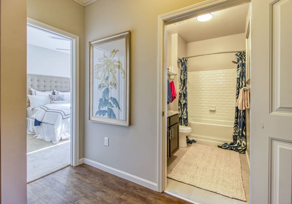 Hallway with wood flooring, connecting the bedroom to the full bathroom with shower and bathtub at Everwood at The Avenue in Murfreesboro, Tennessee