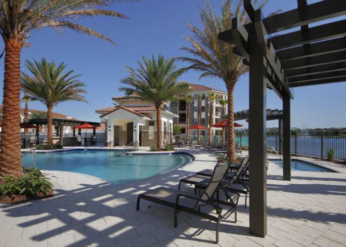 Sparkling pool surrounded by palm trees and chic seating areas at Messina Luxury Apartments in New Smyrna Beach, Florida
