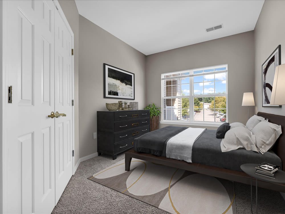 Cozy bedroom featuring large window, stylish dresser, and plush area rug at 43 North Apartments in Grand Haven, Michigan