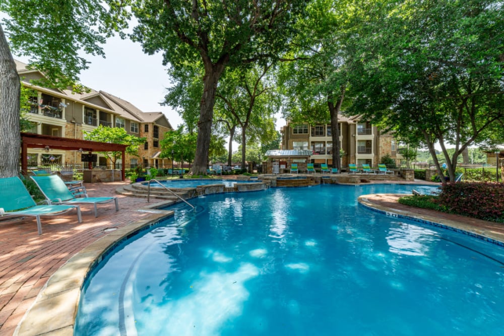 Resort style pool surrounded by lounge chairs at Marquis at Bellaire Ranch in Fort Worth, Texas