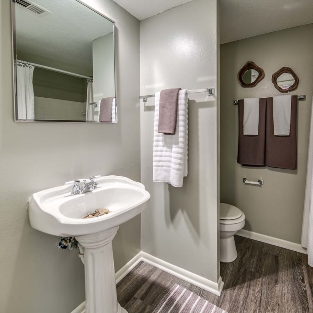 Updated bathroom with hardwood flooring at London House Apartments in Lenexa, Kansas