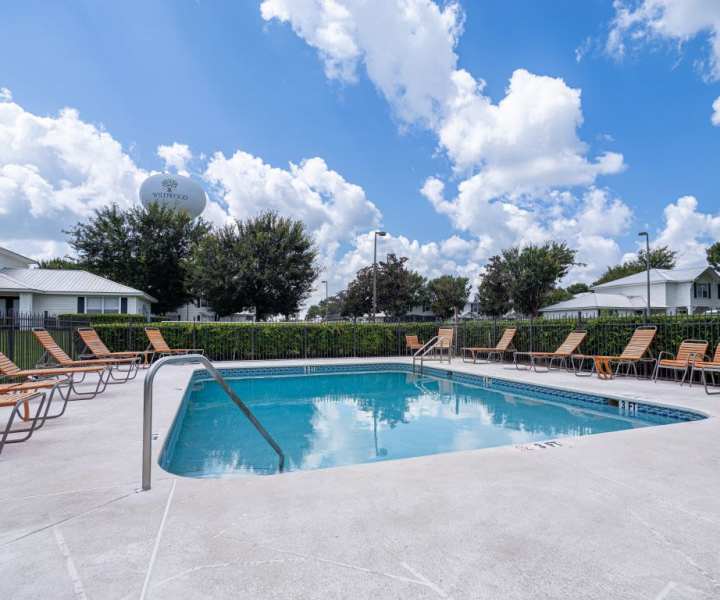 Resort-style swimming pool with multiple lounge chairs at Cypress Commons in Wildwood, Florida