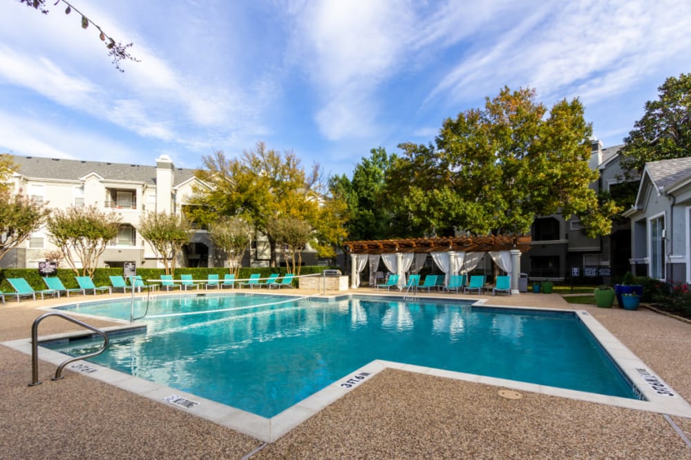 Pool with volleyball net, lounge chairs, and gazebo area at Marquis at Stonegate in Fort Worth, Texas