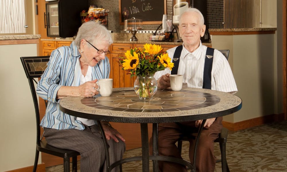 Resident couple drinking coffee and laughing at Villa at the Lake in Conneaut, Ohio