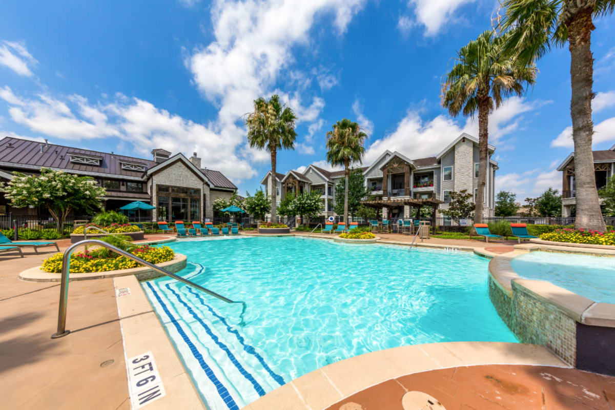 Resort style swimming pool surrounded by lounge chairs at Marquis at Sugar Land in Sugar Land, Texas