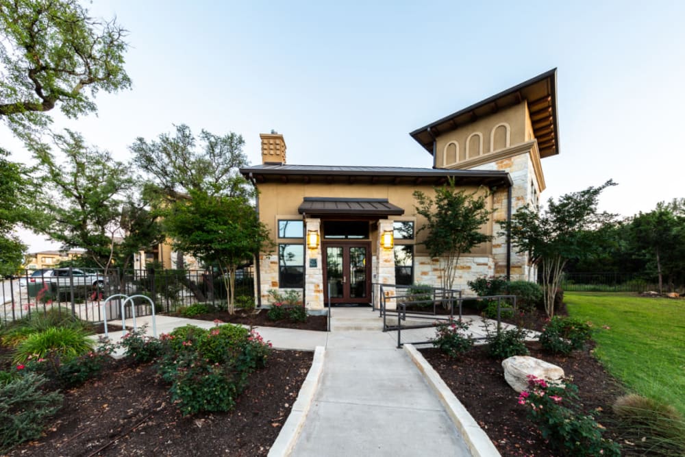 Well manicured clubhouse entrance lined with flowers and plants at Marquis at Barton Trails in Austin, Texas
