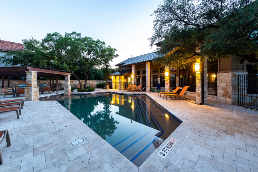 Pool area with lounge chairs at sunset at Marquis at Barton Trails in Austin, Texas