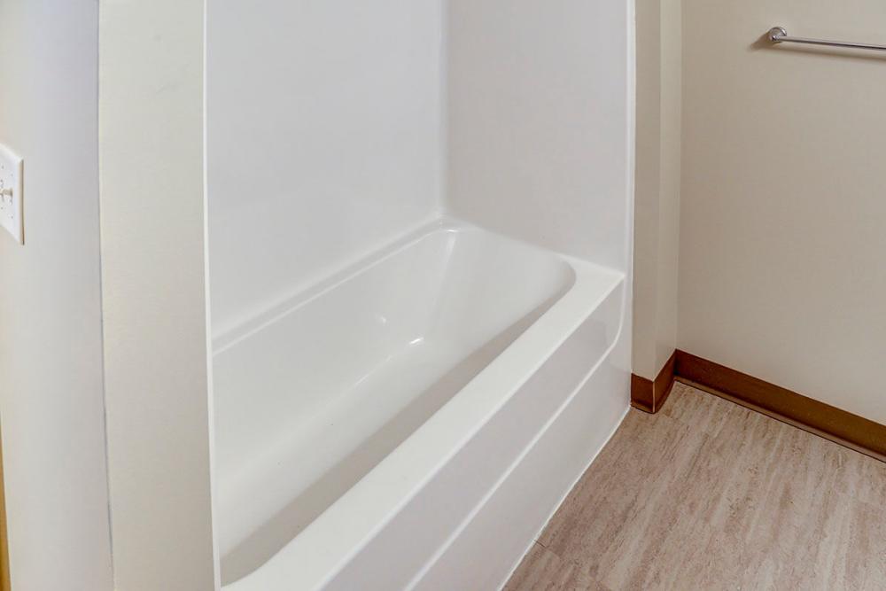 Bathtub with white surround and light wood-style flooring in a modern bathroom at Pebblecreek Crossing in Richmond, Kentucky