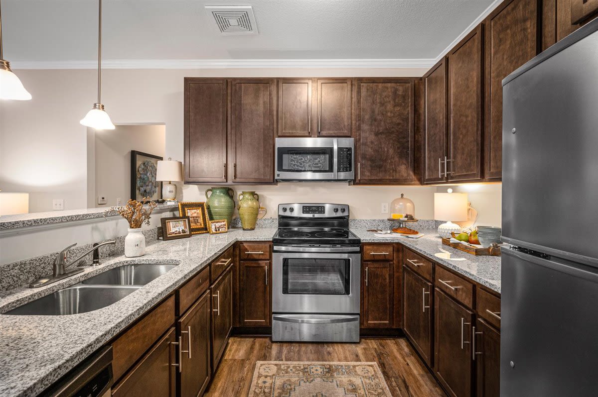 Stainless steel appliances and dark wood cabinets in an apartment kitchen at Bowman Station in Macon, Georgia