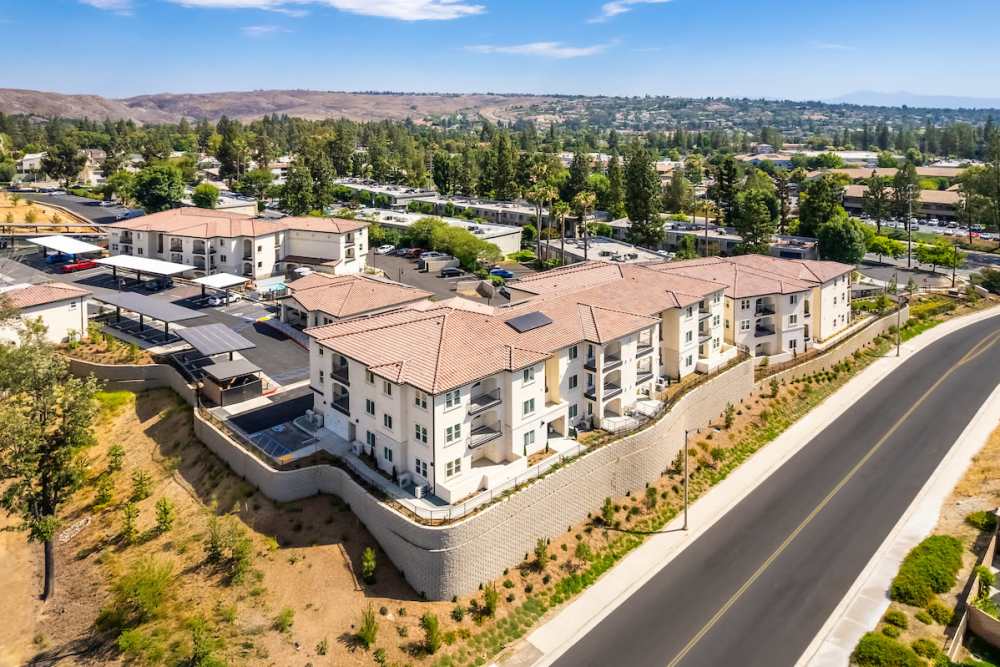 Drone image with mountains, greenery and car parking at Canyon Bluffs Apartment Homes in Riverside, California