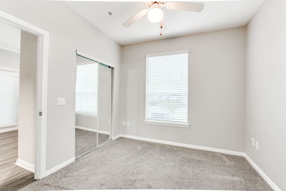 An apartment bedroom with a ceiling fan at Compass at Windmill Lakes in Houston, Texas