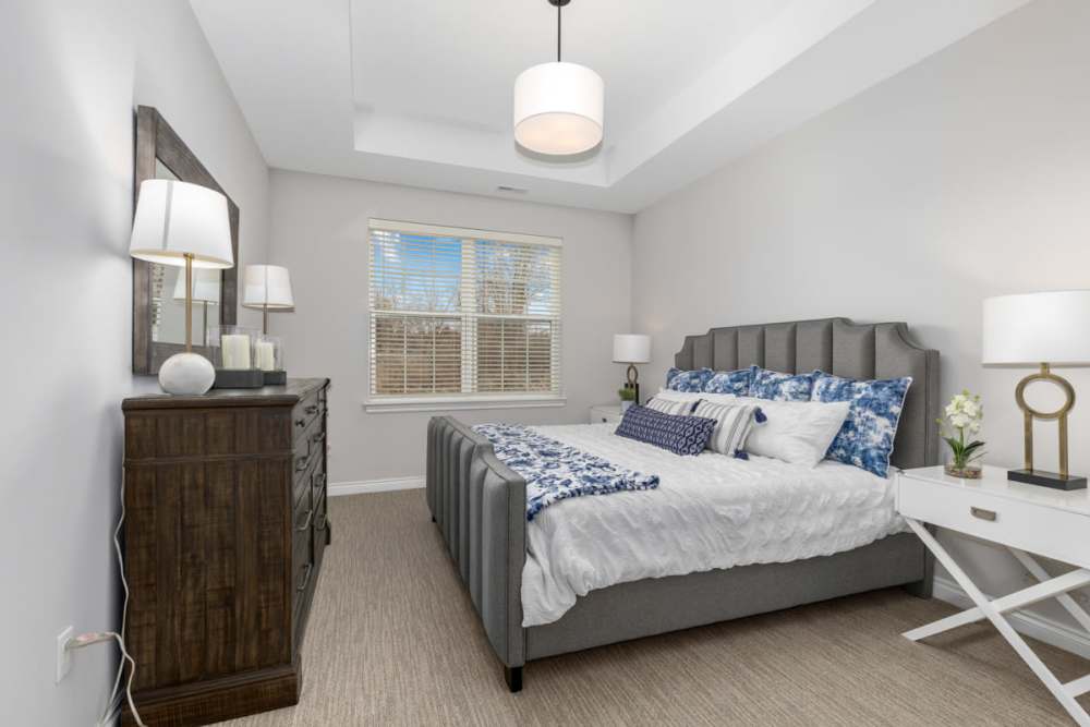 Well-furnished bedroom with floor-to-ceiling windows in a model home at Encore at Heritage Woods in Dexter, Michigan
