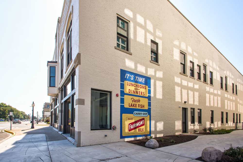 Historic building exterior with large windows and colorful signage on the side at Lloyd House II in Menominee, Michigan