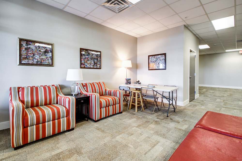 Bright lounge area with striped chairs, table, and wall art, featuring cozy, inviting atmosphere at Lloyd House II in Menominee, Michigan