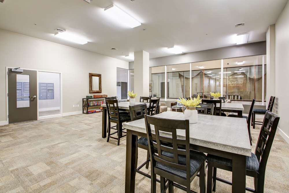 Modern community lounge with tables, chairs, and a large window showcasing a cozy reading area at Lloyd House II in Menominee, Michigan