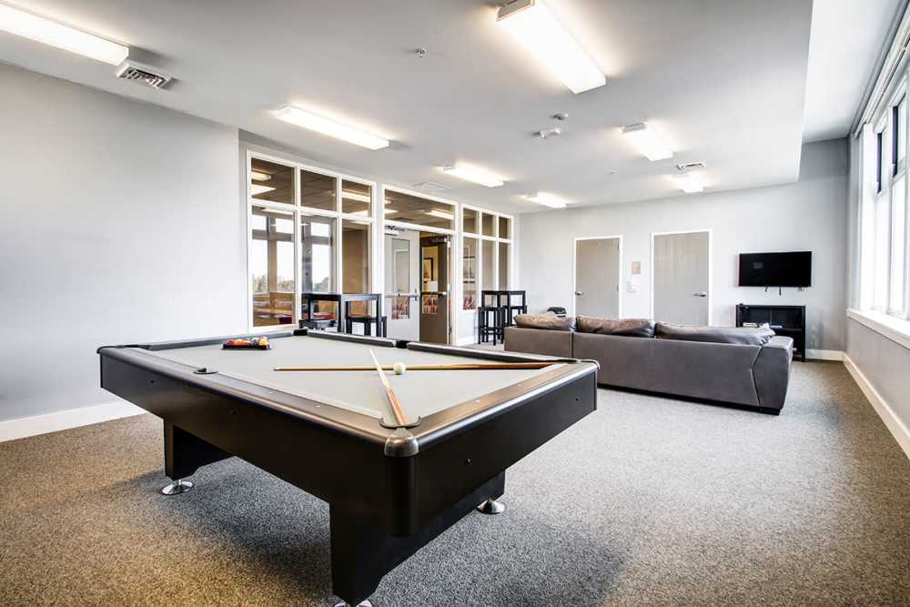 Game room with pool table, seating area, and large windows for natural light at Lloyd House II in Menominee, Michigan