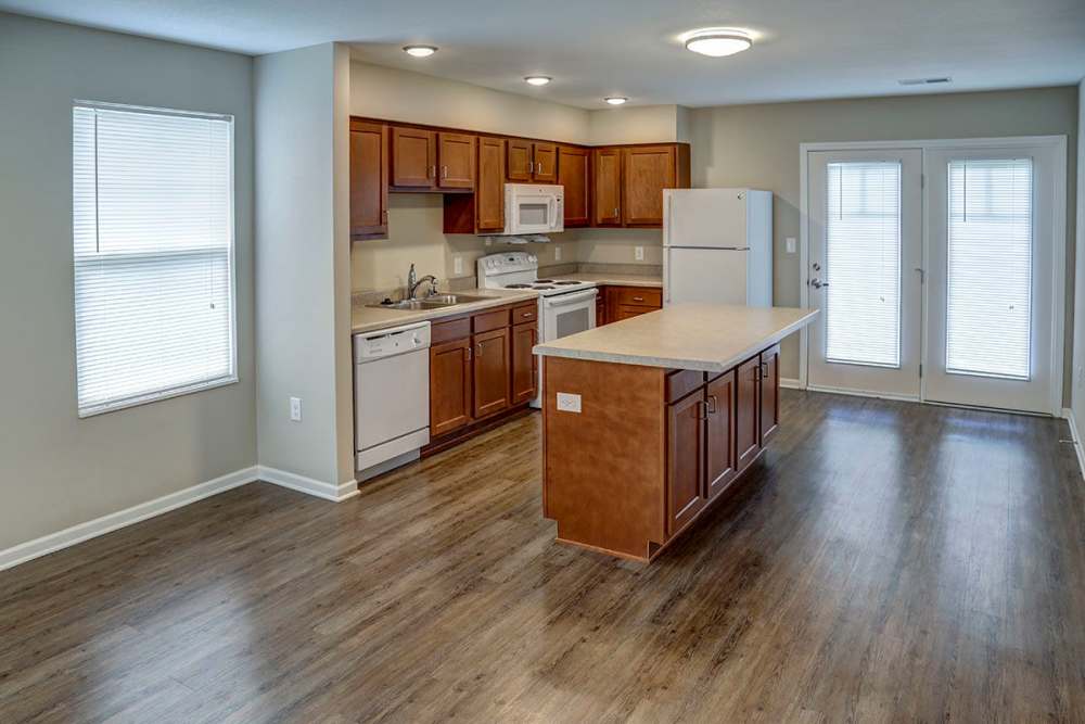 Open layout kitchen with granite countertops, stainless steel appliances, and wood-style flooring at Brea's Crossing Senior Living I in Shelbyville, Kentucky
