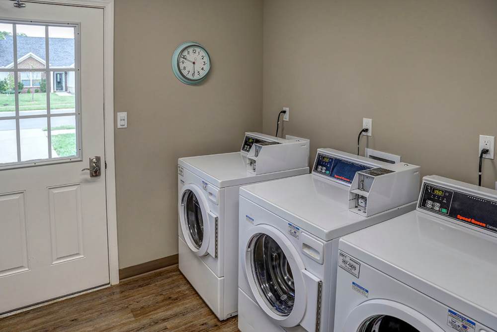 Bright laundry room with modern machines and a door leading outside at Brea's Crossing Senior Living I in Shelbyville, Kentucky