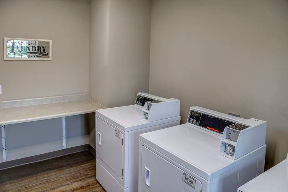 Laundry room with two white washing machines and a folding counter at Brea's Crossing Senior Living I in Shelbyville, Kentucky