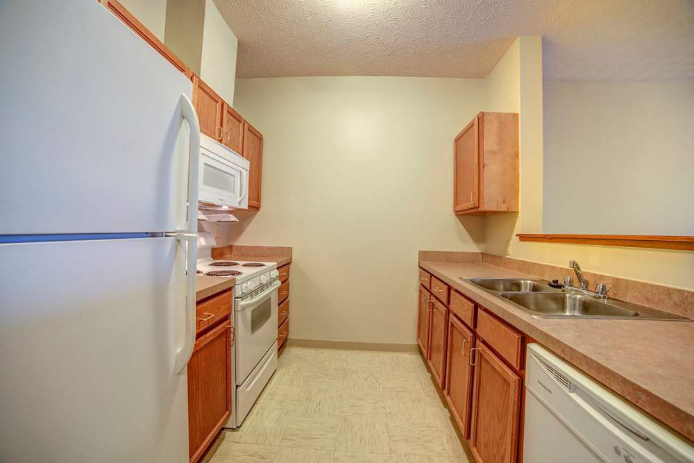Wooden cabinets and white appliances in the kitchen at Brentwood Greene in Kokomo, Indiana